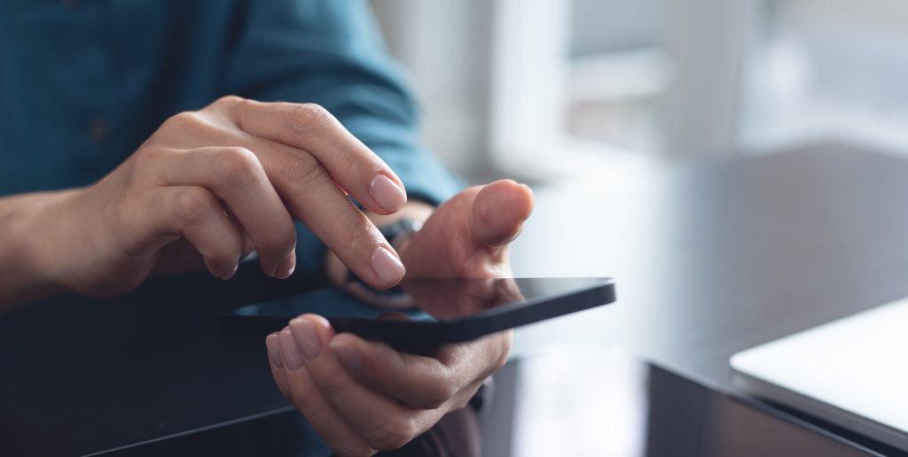 Woman,Using,Mobile,Phone,With,Laptop,Computer,On,Office,Table.