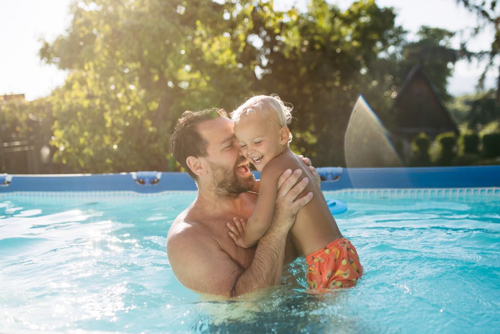 Father,Playing,With,Little,Son,In,Pool.